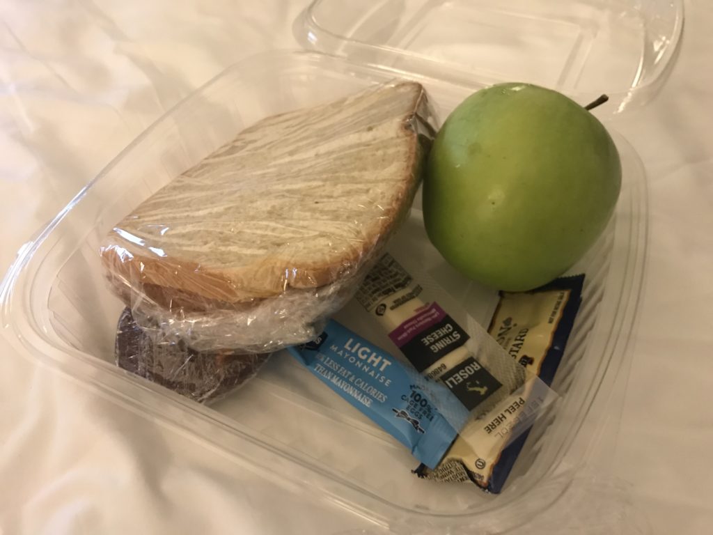 a lunch box with food and a green apple