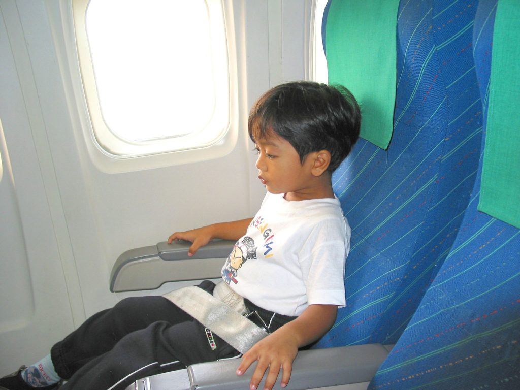 a child sitting in a seat on an airplane
